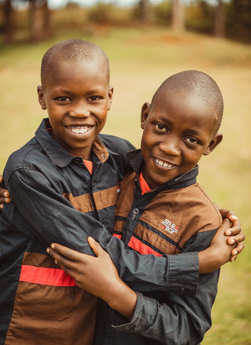 two boys from chariots for hope home in kenya-hugging and smiling for a picture