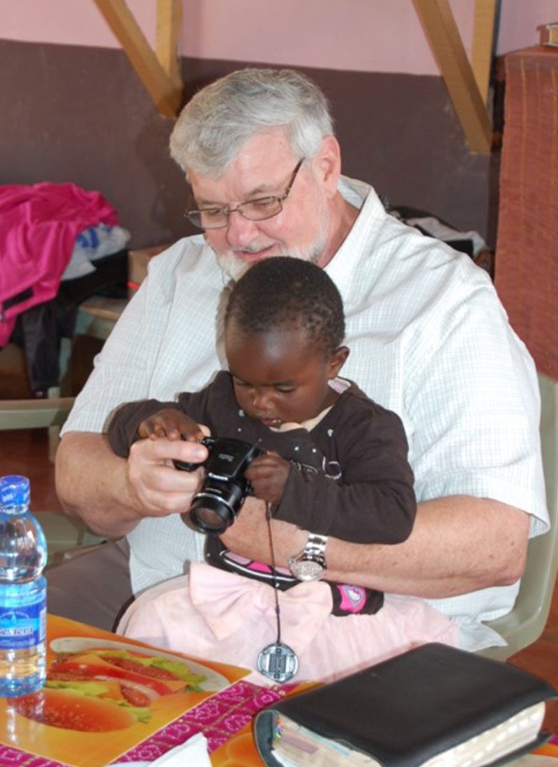 young child in kenya looking at photos on a camera