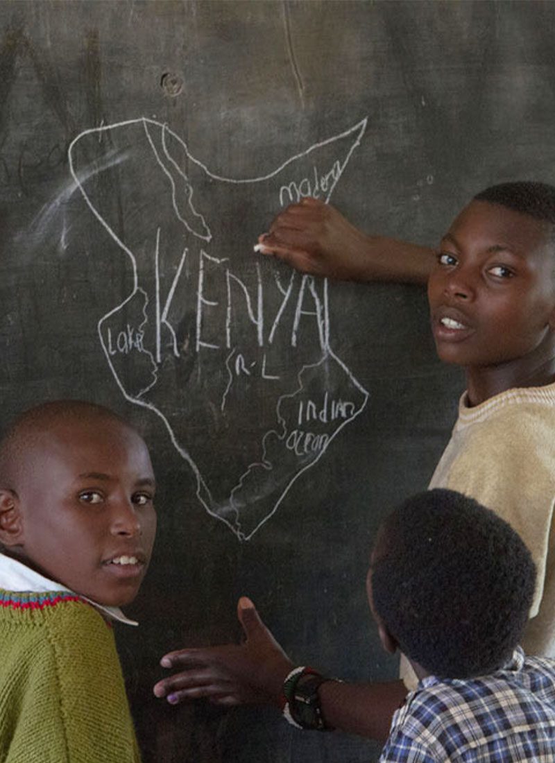 children drawing a map of kenya on a chalkboard